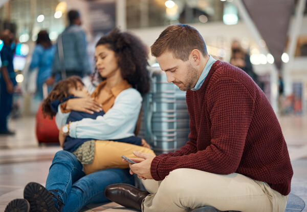 Phone, tired and interracial family waiting at the airport for a delayed flight. Contact, late and .